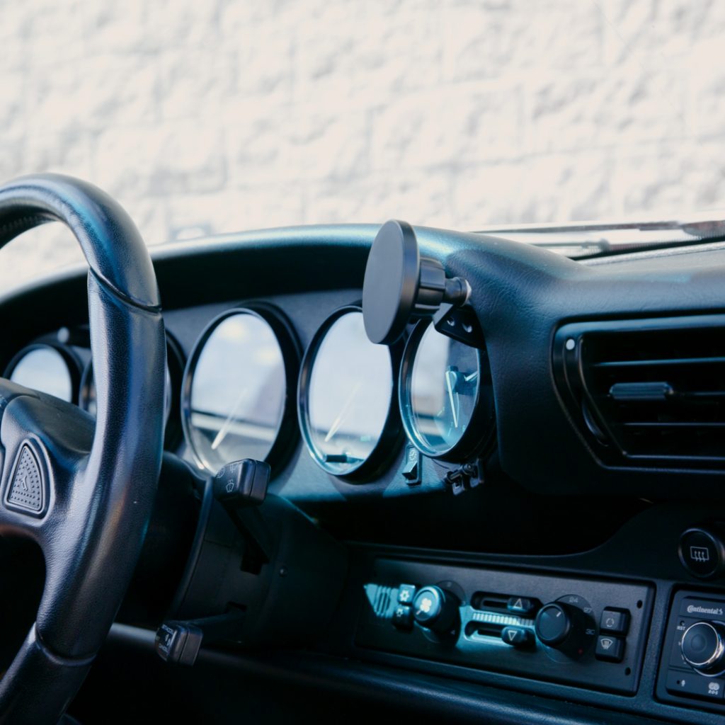 Rinashi Porsche 911 phone holder mounted between dashboard gauges