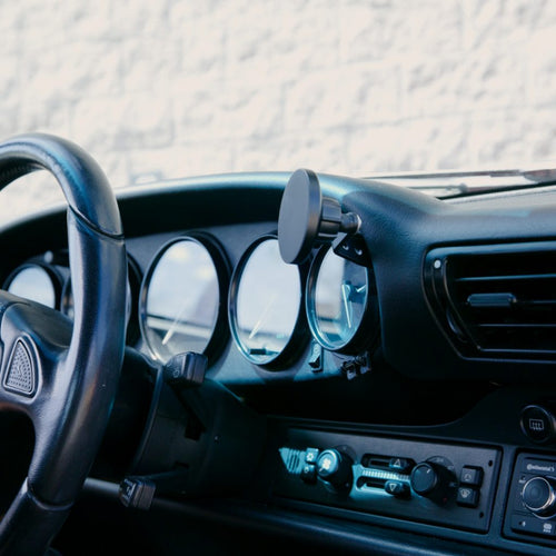 Rinashi Porsche 911 phone holder mounted between dashboard gauges