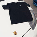 Black Rinashi T-shirt displayed flat on white sports car hood