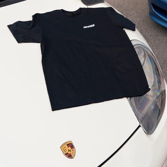 Black Rinashi T-shirt displayed flat on white sports car hood