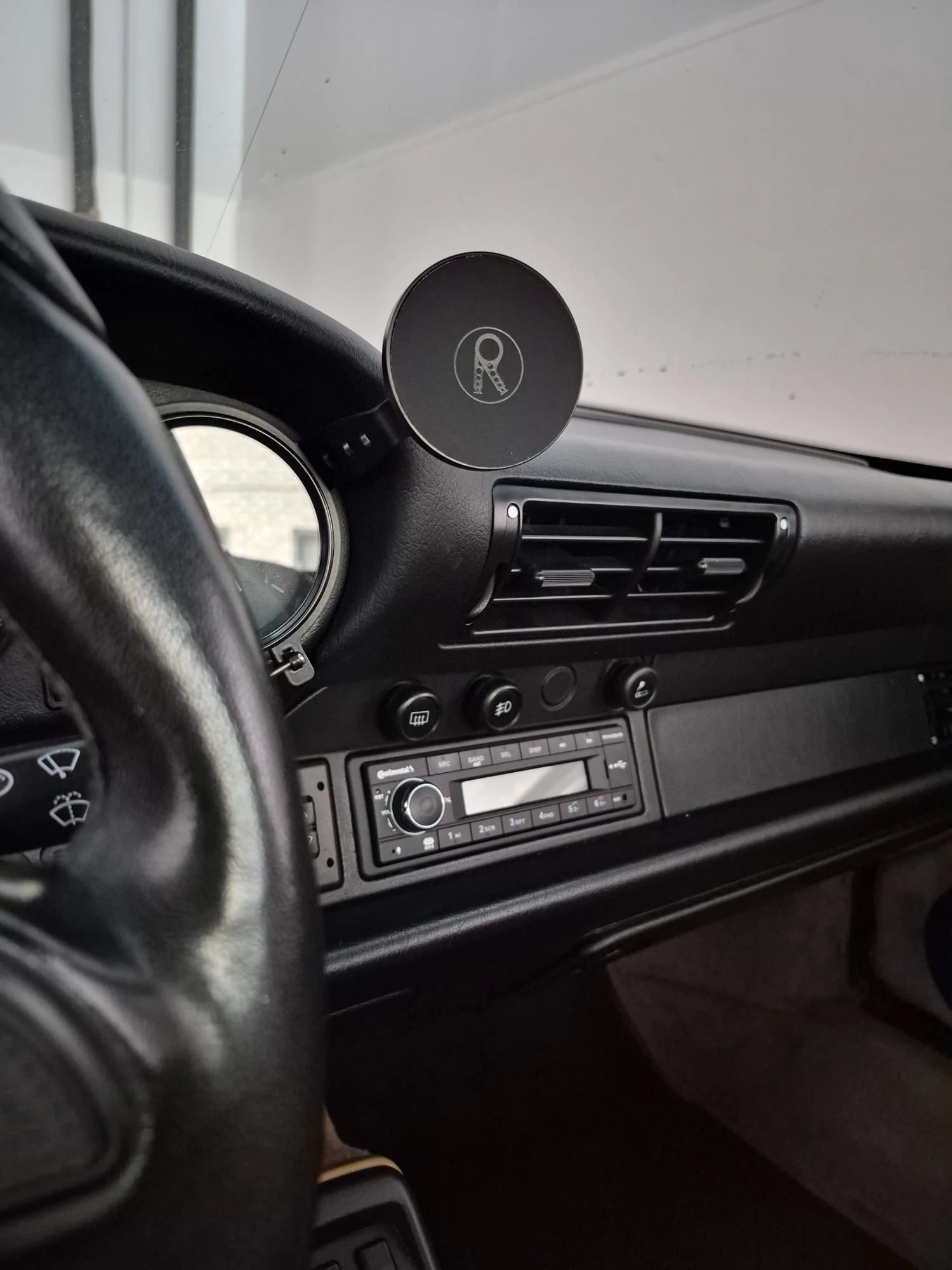 Close-up of the Rinashi magnetic phone mount installed beside a Porsche 911 gauge